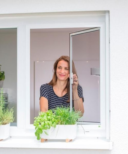 Een vrolijke vrouw die uit haar raam kijkt.