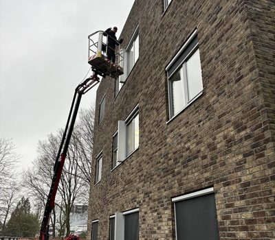 Luxicon staat op een hoogwerker om zonwering te repareren.